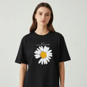 A young woman wearing a classic black short-sleeved t-shirt. The shirt features a large white daisy graphic in the center with a yellow middle, missing one petal at the bottom left. Above the flower, the word "PEACEMINUSONE" is printed in white text with a small lightning bolt logo